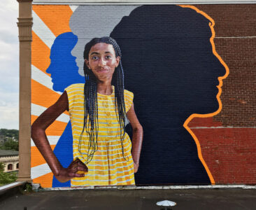 Fearless Girl Mural painted on the exterior of Beacon Charter High School in Woonsocket, RI by Charles C. Clear III and Bonnie Lee Turner